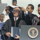 President George Bush, left, is bestowed the ceremonial mantle of an honorary doctor of law degree from Hampton University by the chairman of the board of trustees, Ray LeFlore, center, as the school’s president, Dr. William Harvey, looks on during commencement exercises in Hampton, Va., May 13, 1991. Bush delivered the commencement address. (AP Photo/Steve Helber)